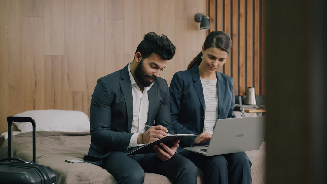 A man and a woman in business suits working on a hotel bed
